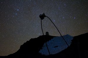 Bei Nacht ist der Parabolspiegel eines Teleskops in den Sternenhimmel gerichtet.