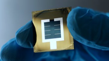 Finger in einem Schutzhandschuh halten eine Solarzellen-Folie