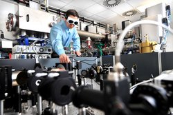 Wissenschaftler mit Schutzbrille im Labor über eine Apparatur gebeugt