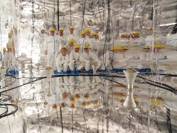 Eine Gruppe von Menschen in weißen Kitteln in einem silbrig glänzenden großen Behälter