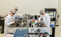 Drei Wissenschaftler stehen an einer Laservorrichtung