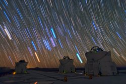 Drei Teleskoptürme unter einem Nachthimmel, der übersät ist von Sternstrahlen